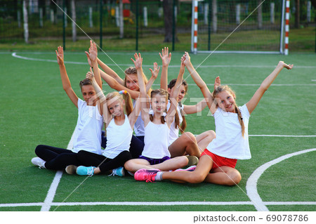 Girls in sportswear are sitting on the playground. 69078786