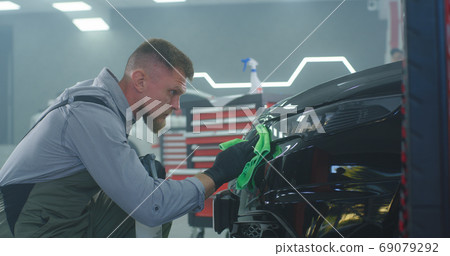 Male technician washing car headlight Male technician washing car headlight 69079292