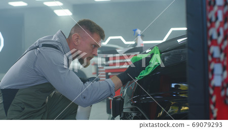 Male technician washing car headlight Male technician washing car headlight 69079293