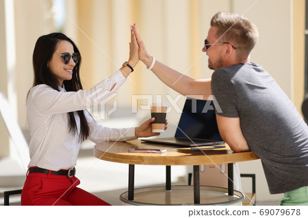 Smiling man and woman greet high five agreement. Smiling man and woman greet high five agreement. 69079678