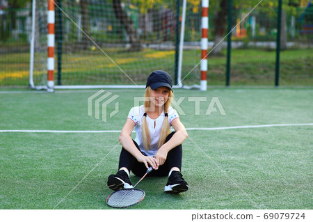 Girl with a racket in her hands on the sports field. Girl with a racket in her hands on the sports field. 69079724