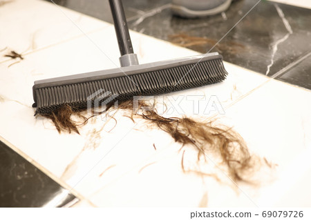 Floor brush is used to sweep cut hair in salon closeup Floor brush is used to sweep cut hair in salon closeup 69079726