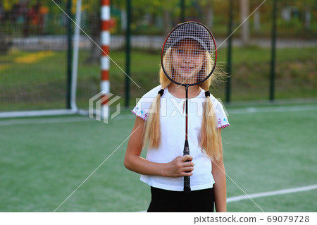 Girl with a racket in her hands on the sports field. Girl with a racket in her hands on the sports field. 69079728