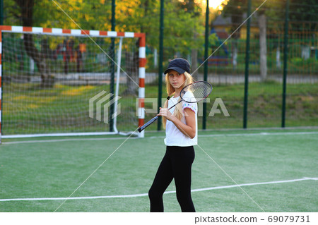 Girl with a racket in her hands on the sports field. 69079731