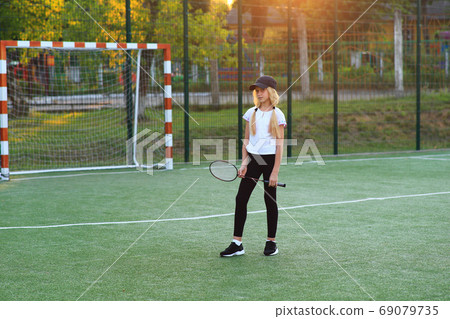 Girl with a racket in her hands on the sports field. Girl with a racket in her hands on the sports field. 69079735