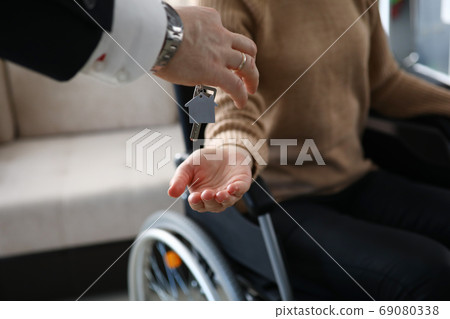 Female hand hold give key with keychain from new house and give to desabled. 69080338