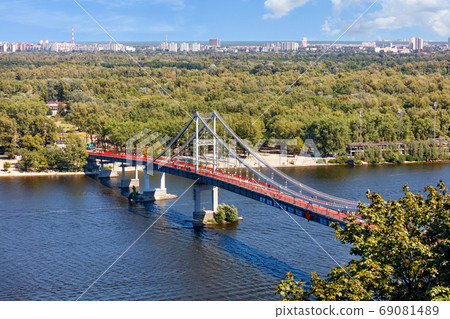 Pedestrian park bridge over the Dnipro river in Kyiv on a sunny summer day. 69081489