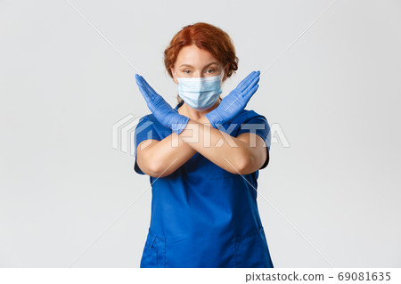 Medical workers, covid-19 pandemic, coronavirus concept. Confident and serious female doctor disapprove or disagree, wear face mask and gloves, making cross stop gesture, prohibit or forbid 69081635
