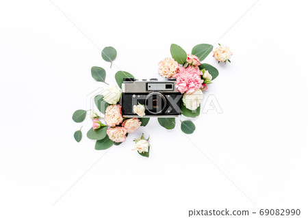 Vintage retro camera, decor of pink and beige rose flower buds pattern on white background. Flat lay, top view Vintage retro camera, decor of pink and beige rose flower buds pattern on white background. Flat lay, top view 69082990