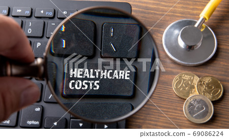 HEALTHCARE COSTS. Computer keyboard on a wooden table HEALTHCARE COSTS. Computer keyboard on a wooden table 69086224