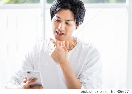 A young man looking at the screen of the smartphone A young man looking at the screen of the smartphone 69086677
