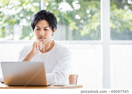 Young man looking at laptop screen Young man looking at laptop screen 69087565