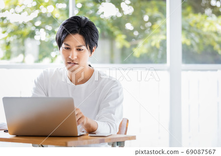 Young man doing deskwork towards a laptop 69087567