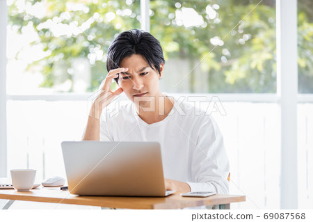 Young man with a stern look looking at the laptop screen 69087568