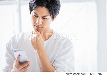 看有嚴肅的神色的一個年輕人智能手機 69087823