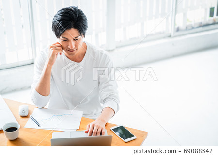 Young man doing deskwork in a bright room Young man doing deskwork in a bright room 69088342