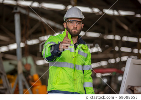 Portrait of male Engineer standing with confident against machine environment in factory Portrait of male Engineer standing with confident against machine environment in factory 69088653