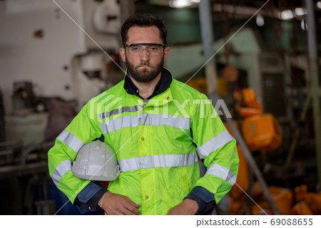Portrait of male Engineer standing with confident against machine environment in factory Portrait of male Engineer standing with confident against machine environment in factory 69088655