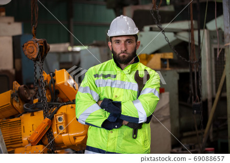 Portrait of male Engineer standing with confident against machine environment in factory Portrait of male Engineer standing with confident against machine environment in factory 69088657