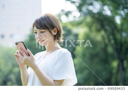 使用手機時到戶外散步的年輕女子 使用手機時到戶外散步的年輕女子 69089433