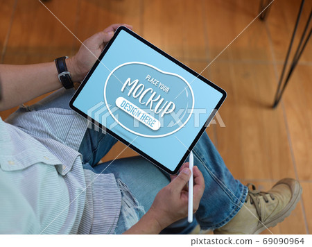 Male worker using mock up tablet on his lap while relaxed sittin Male worker using mock up tablet on his lap while relaxed sittin 69090964
