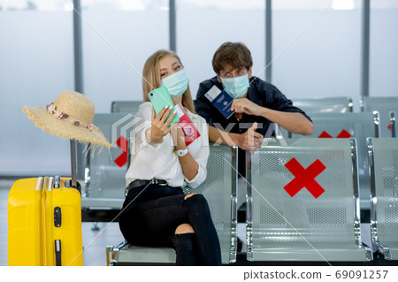 Couple Caucasian lovers man and woman with mask sit on chair with social distance selfie together Couple Caucasian lovers man and woman with mask sit on chair with social distance selfie together 69091257