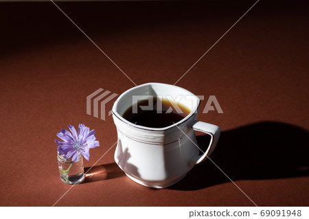 Chicory drink or coffee in white cup with chicory flower on a brown background. 69091948