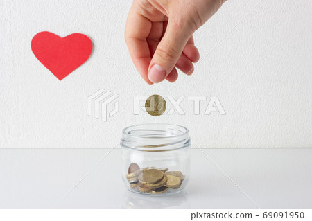 Hand putting coin in a jar, saving money or donation 69091950
