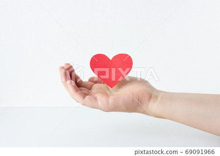 Red heart symbol in woman hand. White background. Love and charity concept. Red heart symbol in woman hand. White background. Love and charity concept. 69091966