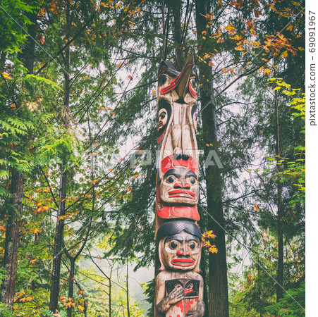 Alaska totem pole carving art sculture tourist travel destination forest background. Ketchikan, Juneau, Skagway, Vancouver. 69091967