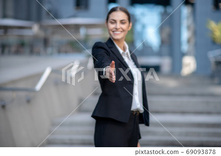 Beautiful woman in a suit stretching her hand in greeting Beautiful woman in a suit stretching her hand in greeting 69093878