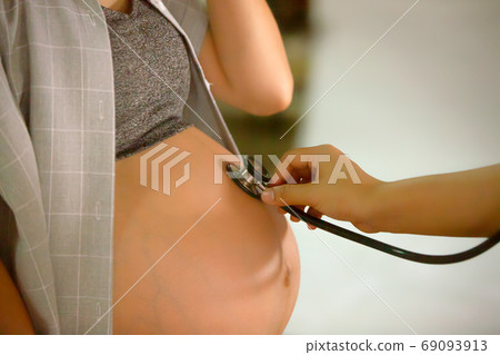 close up of a doctor holding stethoscope on pregnant women close up of a doctor holding stethoscope on pregnant women 69093913