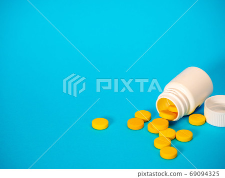 Yellow pills and plastic white bottle 69094325