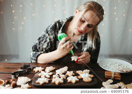 Woman decorating Christmas gingerbread cookies Woman decorating Christmas gingerbread cookies 69095376