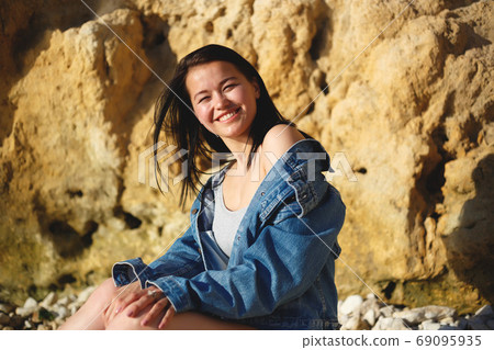 portrait of a woman in a denim jacket on a background of yellow rock 69095935