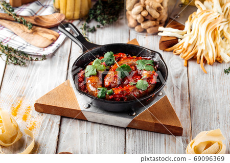 Large sausage in tomato sauce in cast iron pan Large sausage in tomato sauce in cast iron pan 69096369