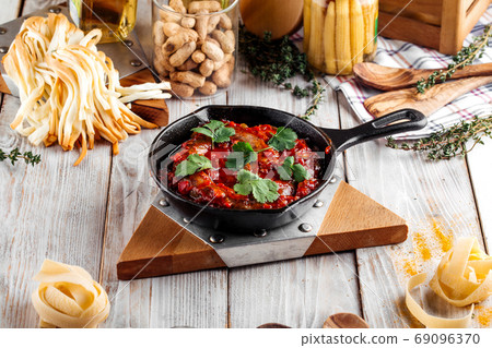 Large sausage in tomato sauce in cast iron pan Large sausage in tomato sauce in cast iron pan 69096370