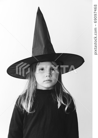 Little girl in black costume with witch hat, black and white Little girl in black costume with witch hat, black and white 69097468