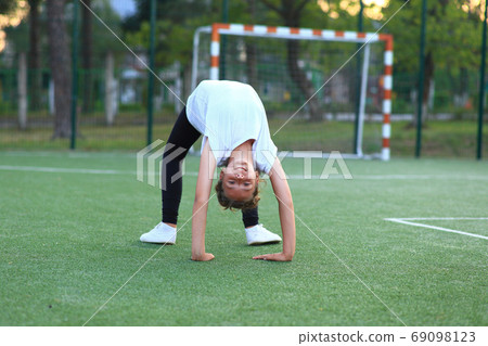 girl is engaged in gymnastics on the sports field. girl is engaged in gymnastics on the sports field. 69098123