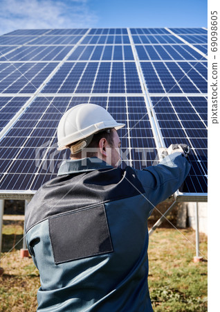 Male technician installing photovoltaic blue solar module. Male technician installing photovoltaic blue solar module. 69098605