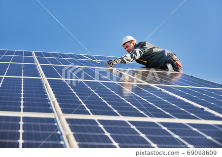 Solar installer working under beautiful blue sky. Solar installer working under beautiful blue sky. 69098609
