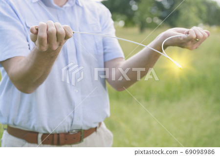 Man dowsing wirh dividing rod to locate ground water Man dowsing wirh dividing rod to locate ground water 69098986