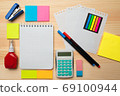 The top view of creative desk with office accessories, notebooks and colorful stickers. Wooden background with copy space for inscription. 69100944