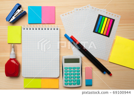 The top view of creative desk with office accessories, notebooks and colorful stickers. Wooden background with copy space for inscription. 69100944