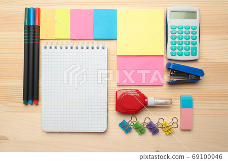 The top view of creative desk with office accessories, notebooks and colorful stickers. Wooden background with copy space for inscription. The top view of creative desk with office accessories, notebooks and colorful stickers. Wooden background with copy space for inscription. 69100946