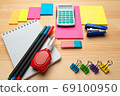 The top view of creative desk with office accessories, notebooks and colorful stickers. Wooden background with copy space for inscription. 69100950
