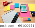 The top view of creative desk with office accessories, notebooks and colorful stickers. Wooden background with copy space for inscription. 69100951