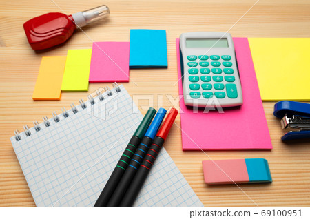 The top view of creative desk with office accessories, notebooks and colorful stickers. Wooden background with copy space for inscription. 69100951