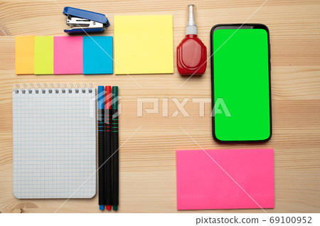 The top view of creative desk with office accessories, notebooks and colorful stickers. Wooden background with copy space for inscription. The top view of creative desk with office accessories, notebooks and colorful stickers. Wooden background with copy space for inscription. 69100952