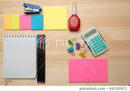 The top view of creative desk with office accessories, notebooks and colorful stickers. Wooden background with copy space for inscription. 69100953